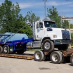 a photo showing a made in Canada new JT Fabrication roll off truck body loaded on a flatbed